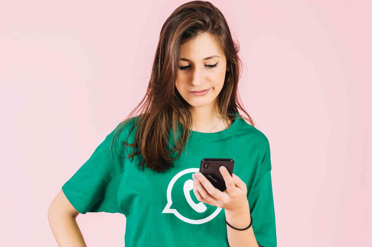 ragazza con smartphone e maglietta con simbolo Whatsapp