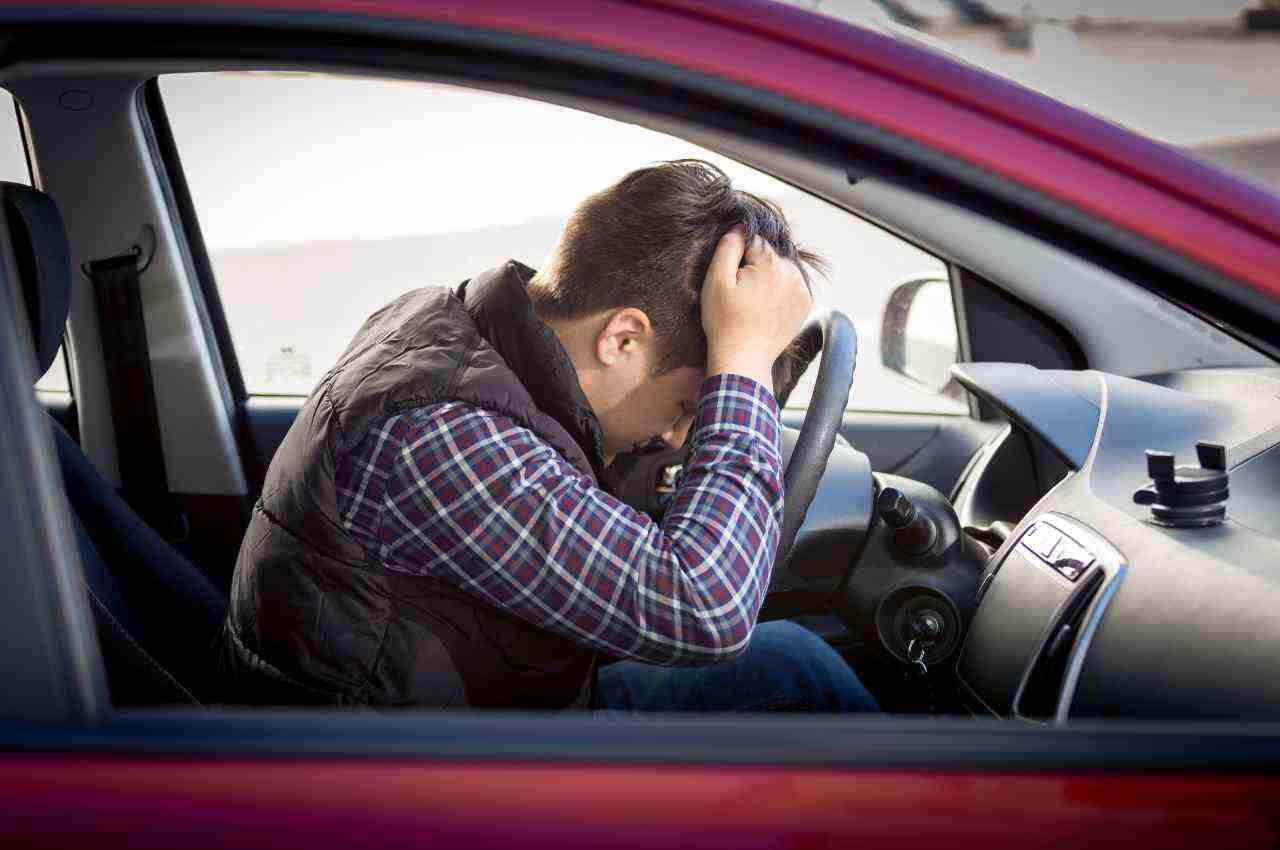 uomo disperato in auto