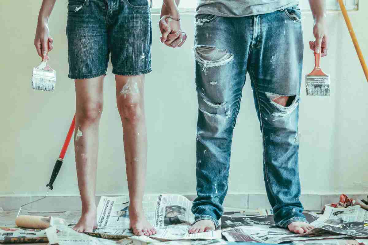 Un ragazzo e una ragazz si tengono per mano mentre dipingono casa